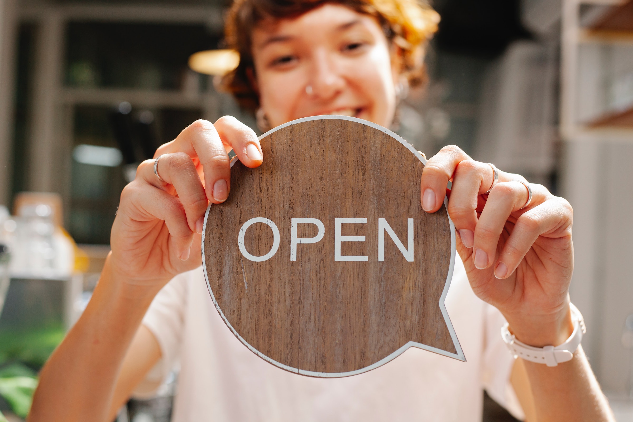 Preencabezado - señora con un cartel de madera de Open