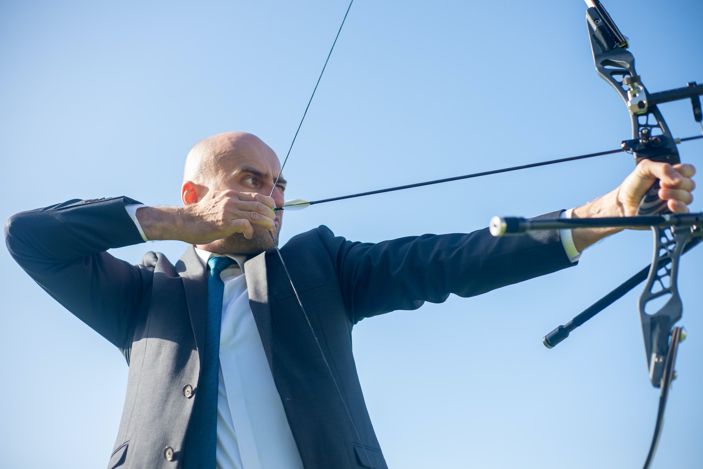 Hombre con traje practicando tiro con arco - Foto de Kampus Production en Pexels